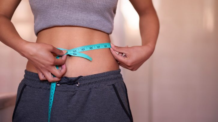 Cropped shot of an unrecognizable young woman measuring her waist